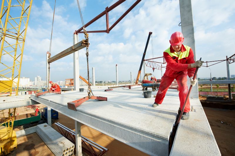 worker installing a concrete slab on a commercial building under construction